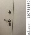 Minimalist white door with modern steel handle and lock, closeup apartment entrance, clean secure home, safe access, architectural detail, property, real estate, and lifestyle concept 130731360