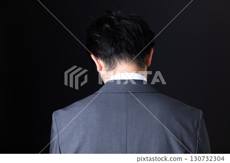The back of a middle-aged businessman in a suit who is worried 130732304