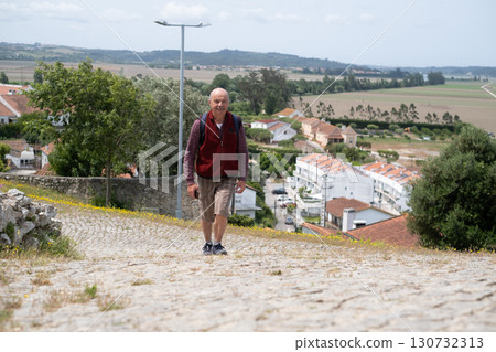 elderly man walking in Portuguese village and enjoying the views elderly man walking in Portuguese village and enjoying the views 130732313