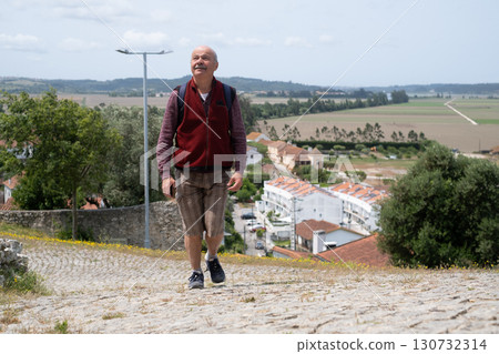 elderly man walking in Portuguese village and enjoying the views elderly man walking in Portuguese village and enjoying the views 130732314