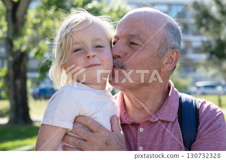 grandfather holding granddaughter in arms and kissing her on the cheek grandfather holding granddaughter in arms and kissing her on the cheek 130732328