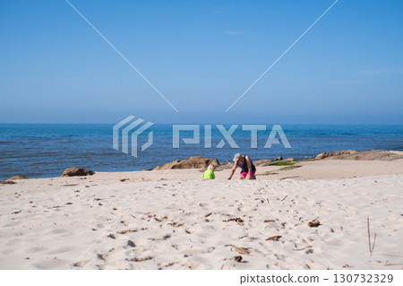 girl playing with grandfather in sand on the beach during summer holidays 130732329