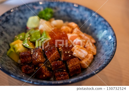 Donburi, a Japanese rice bowl dish of seafood. Including raw fish such as Salmon, Ikura, Unagi, and Avocado Donburi, a Japanese rice bowl dish of seafood. Including raw fish such as Salmon, Ikura, Unagi, and Avocado 130732524