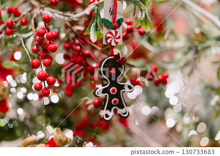 A gingerbread man ornament hangs on a Christmas tree 130733683