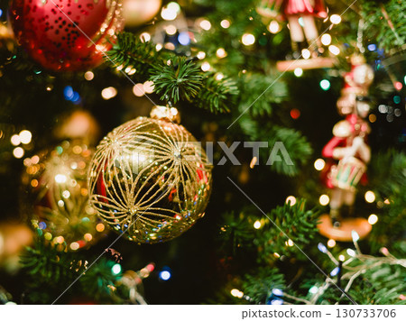 A gold ornament hangs on a Christmas tree A gold ornament hangs on a Christmas tree 130733706