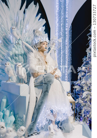 A woman is sitting on a throne in a room with a Christmas tree 130733727