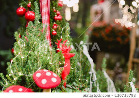 A red mushroom and a red deer are sitting in a pot with green plants 130733798