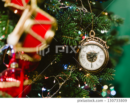 A gold and white clock hanging from a green background A gold and white clock hanging from a green background 130733809