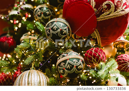 A Christmas tree with many ornaments including a red ball with a gold trim A Christmas tree with many ornaments including a red ball with a gold trim 130733836