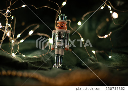 A small, wooden nutcracker is sitting on a green cloth 130733862