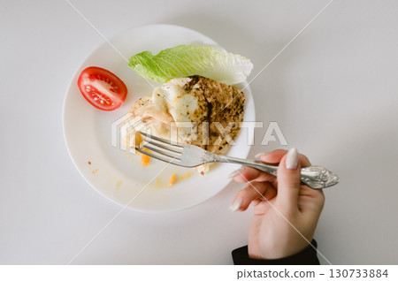 A person is eating a salad with a fork 130733884