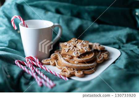 A plate of gingerbread cookies and a mug of coffee sit on a green cloth. Christmas A plate of gingerbread cookies and a mug of coffee sit on a green cloth. Christmas 130733920