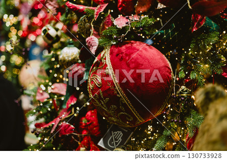 A red ball ornament hangs on a Christmas tree A red ball ornament hangs on a Christmas tree 130733928