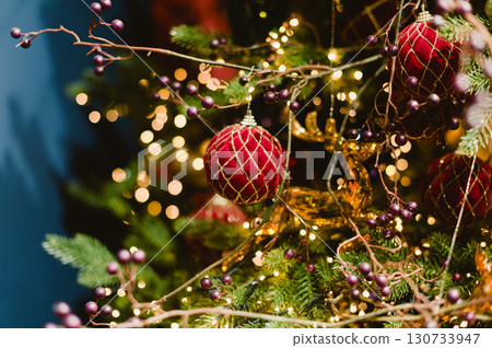 A red ball ornament hangs on a Christmas tree A red ball ornament hangs on a Christmas tree 130733947