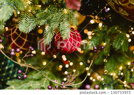 A red ball ornament hangs on a Christmas tree A red ball ornament hangs on a Christmas tree 130733955