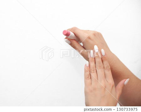 A woman is holding a pink lip balm in her hand A woman is holding a pink lip balm in her hand 130733975