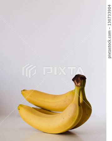 Three bananas are sitting on a white table Three bananas are sitting on a white table 130733984