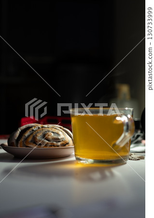 A cinnamon roll with sugar and cup of tea. Breakfast food. Top view. Rustic scene A cinnamon roll with sugar and cup of tea. Breakfast food. Top view. Rustic scene 130733999