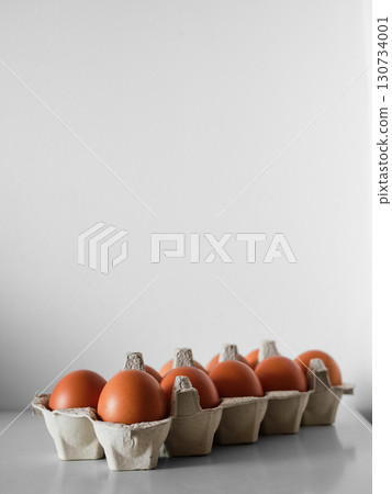 A dozen eggs are sitting in a carton on a counter 130734001