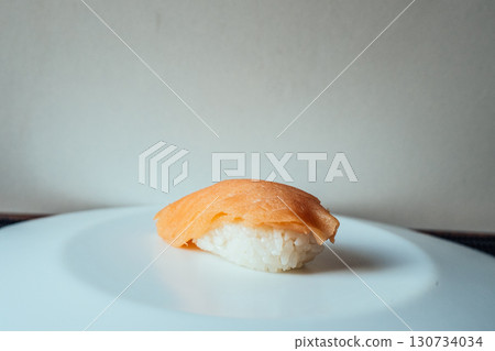 A piece of sushi sits on a white plate 130734034