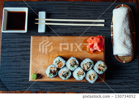 A plate of sushi with chopsticks and a small bowl of sauce A plate of sushi with chopsticks and a small bowl of sauce 130734052