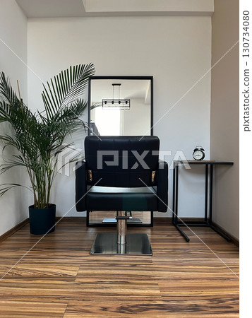 A black chair is in front of a mirror 130734080