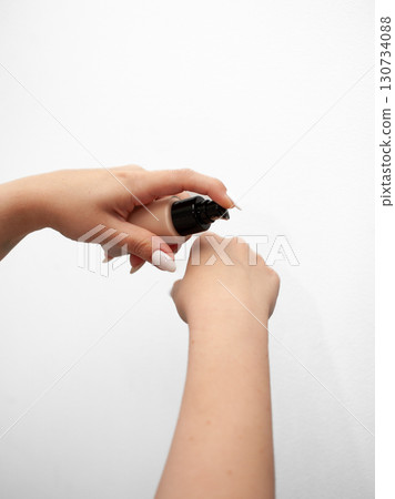 A woman is applying makeup to her face A woman is applying makeup to her face 130734088