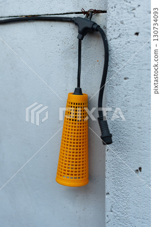 A yellow plastic container with a black cord hanging from it 130734093