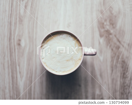 A cup of coffee sits on a wooden table A cup of coffee sits on a wooden table 130734099