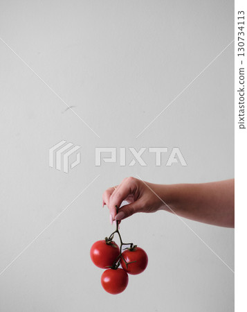 A hand holding three red tomatoes A hand holding three red tomatoes 130734113