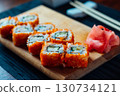A plate of sushi with a garnish of wasabi and cucumber 130734121