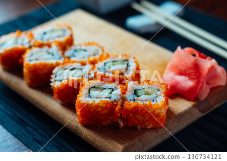 A plate of sushi with a garnish of wasabi and cucumber 130734121