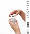 A woman is holding a jar of cream in her hand 130734131