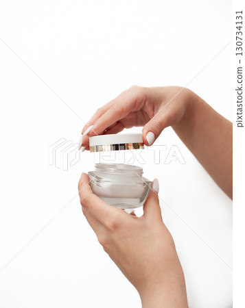 A woman is holding a jar of cream in her hand 130734131