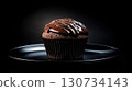Chocolate cupcake with chocolate frosting sits on a black plate 130734143