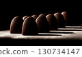 Row of chocolate truffles are lined up on a table. Chocolate bar is a symbol of a sweet treat 130734147