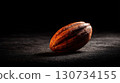Nut is sitting on a dark surface. The nut is brown and has a rough texture. 130734155