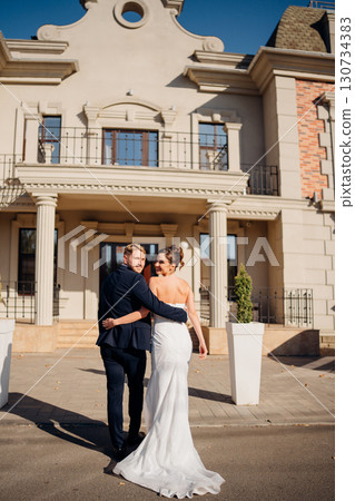 Happy and in love bride and groom at the entrance to a beautiful building Happy and in love bride and groom at the entrance to a beautiful building 130734383