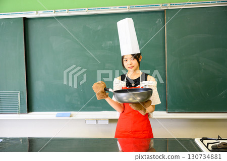 Elementary school girl learning to cook in a cooking class 130734881