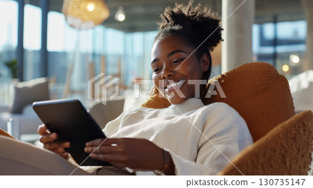 Young black woman engaging with tablet survey interface in a bright, modern workspace. Survey research answer checklist 130735147