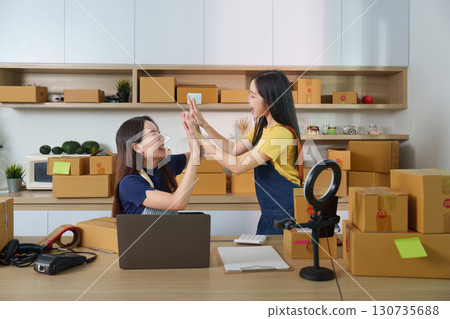 E-commerce Collaboration. Two women celebrating success in a modern workspace. 130735688