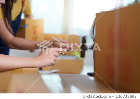 E-commerce Focus. Women working on tasks with attention in a modern workspace. E-commerce Focus. Women working on tasks with attention in a modern workspace. 130735692