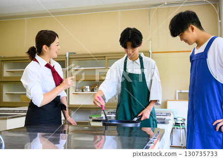 Male students and female instructors learning at a cooking class. Cooking lesson scene. 130735733