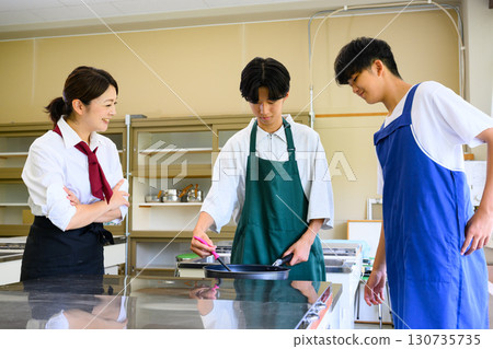 Male students and female instructors learning at a cooking class. Cooking lesson scene. 130735735