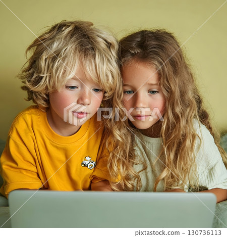 A young boy and girl are intently watching a laptop screen, learning new things and discovering digital education. 130736113