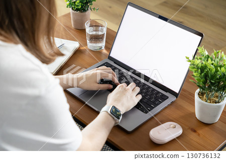 Person's hands typing on a laptop keyboard with a blank screen, showcasing remote work, online learning, and digital productivity in a modern home office setup 130736132