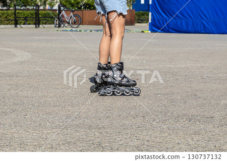Person's lower legs wearing black inline skates featuring a vibrant leopard print design on urban asphalt, conveying active recreation and a dynamic summer lifestyle 130737132