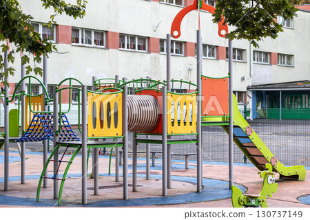 Vibrant modern playground featuring a slide, climbing net, and tunnel, offering a dynamic outdoor space for children's active play and development 130737149