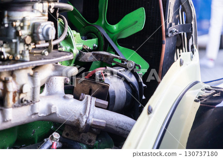 Detailed view of vintage car engine, bright green cooling fan, intricate mechanical parts, symbolizing classic automotive engineering and historical restoration Detailed view of vintage car engine, bright green cooling fan, intricate mechanical parts, symbolizing classic automotive engineering and historical restoration 130737180