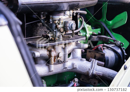 Close-up of a vintage car engine's intricate carburetor, manifold, and green cooling fan, symbolizing classic automotive engineering and power Close-up of a vintage car engine's intricate carburetor, manifold, and green cooling fan, symbolizing classic automotive engineering and power 130737182